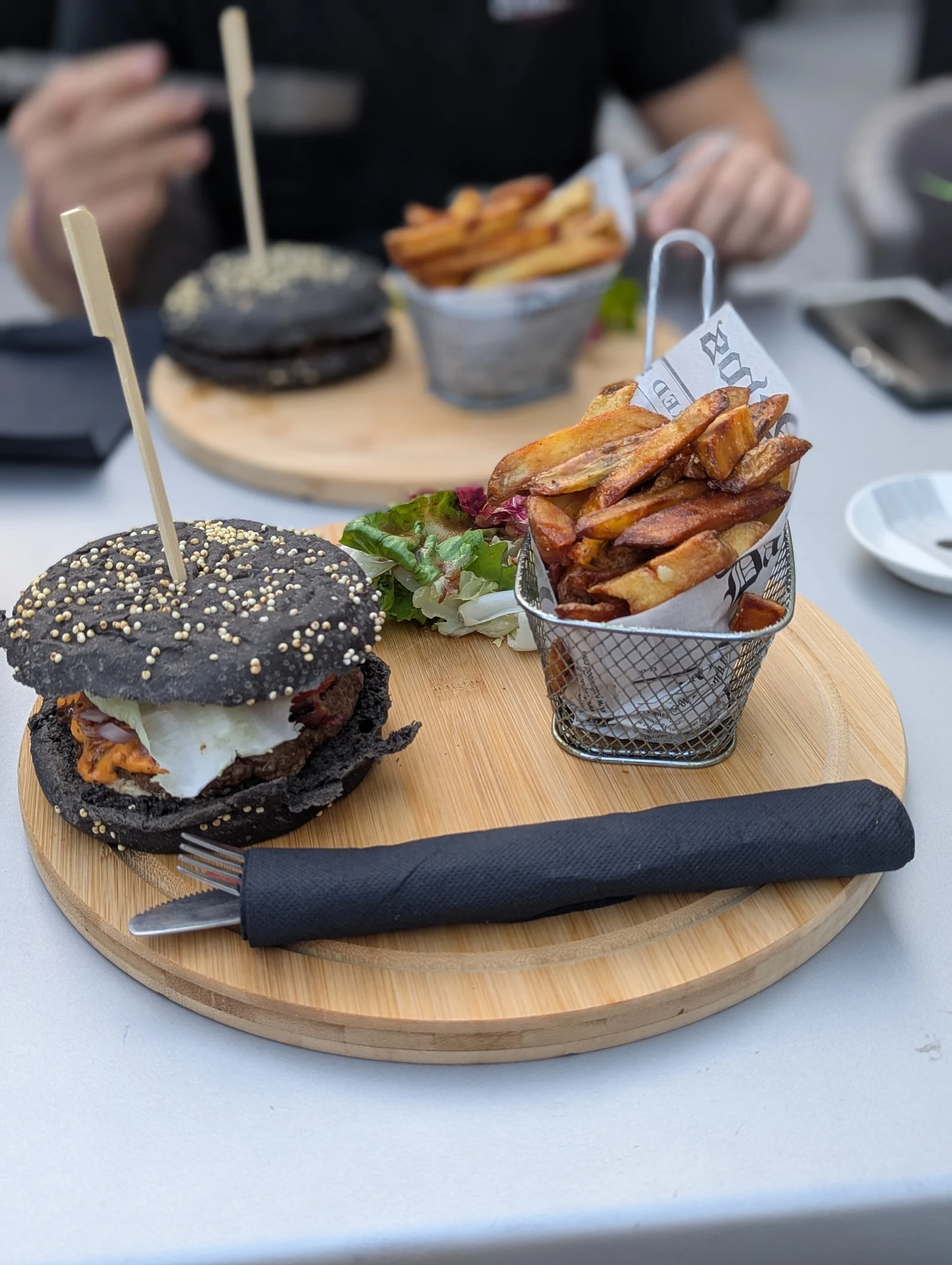 Burgers noirs signature du Grand Burger avec frites maison servies sur planche en bois